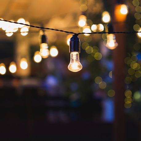 cafe lights hang glowing at night with lit ones in the background