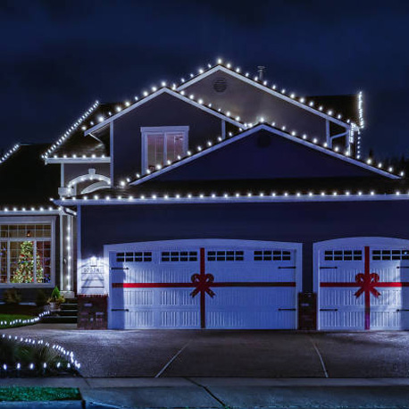 white christmas lights line the rooftop in a perfectly straight line while glowing in the dark night sky