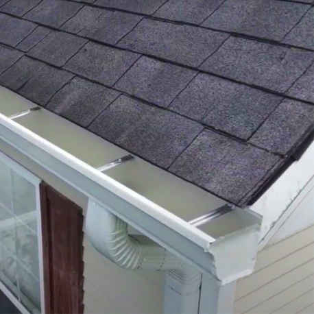 a white house with black composite roof shows off a clean white rain gutter