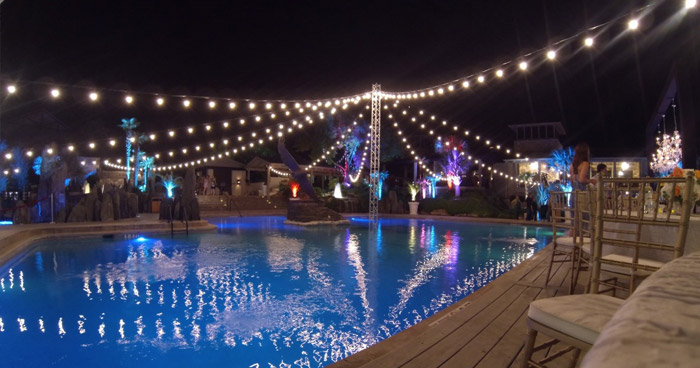 a beautiful backyard illuminated by a custom cafe light installation